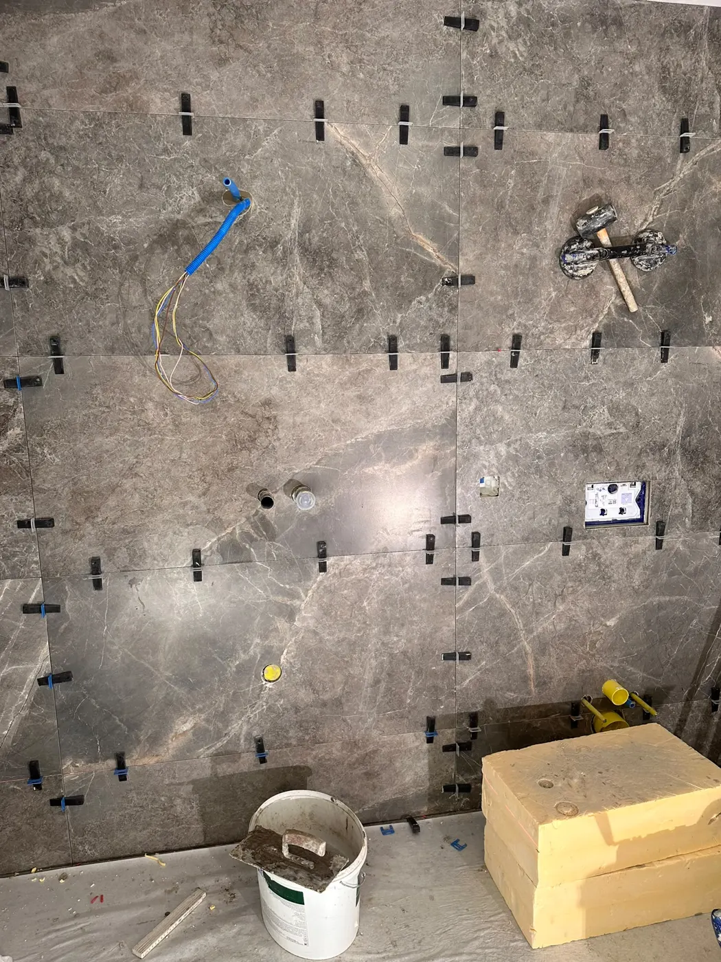 Pose de carrelage effet marbre avec croisillons, chantier en cours